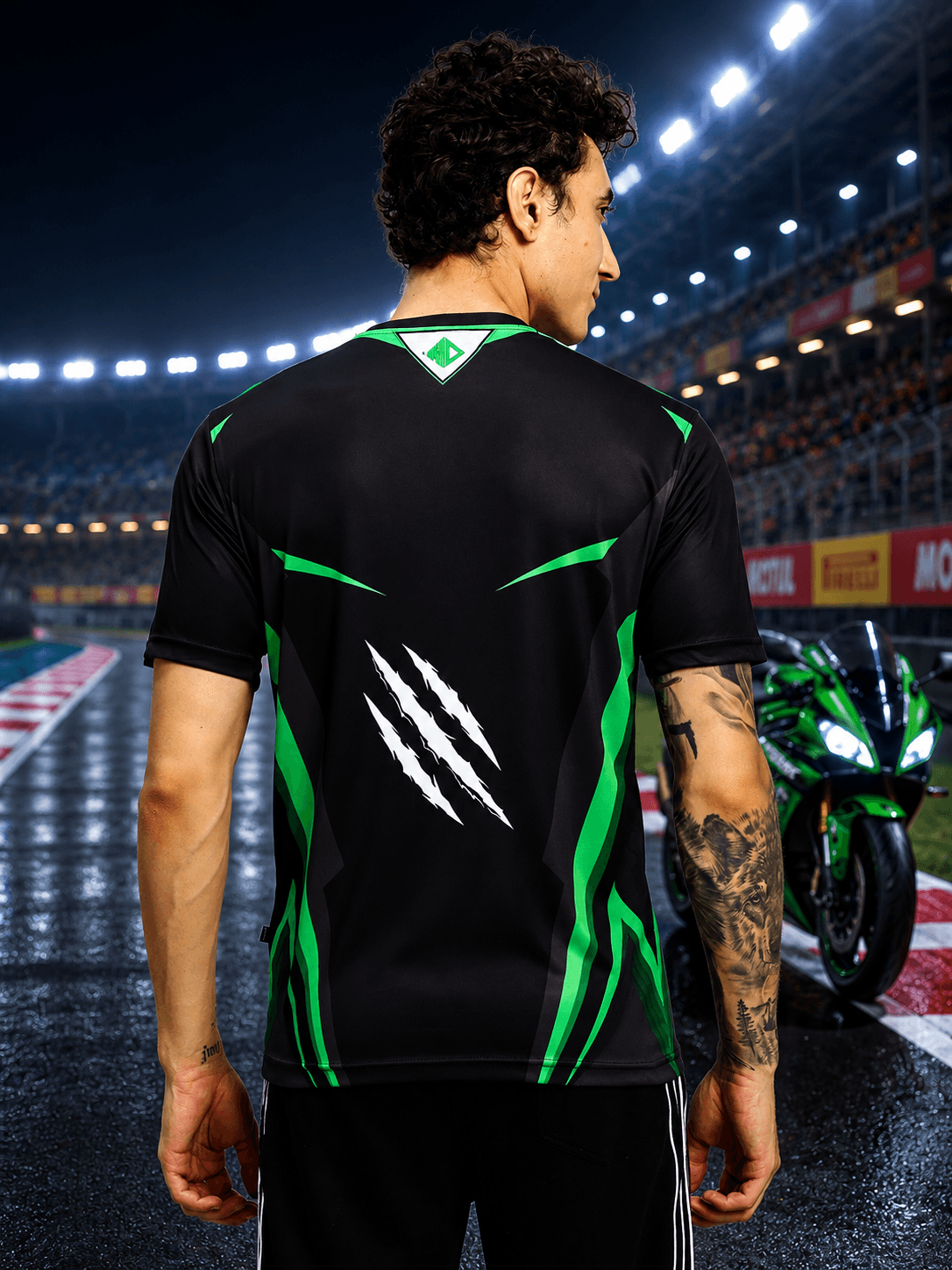Model showcasing the back of the APEX RACING T-SHIRT BLACK against a racetrack backdrop.