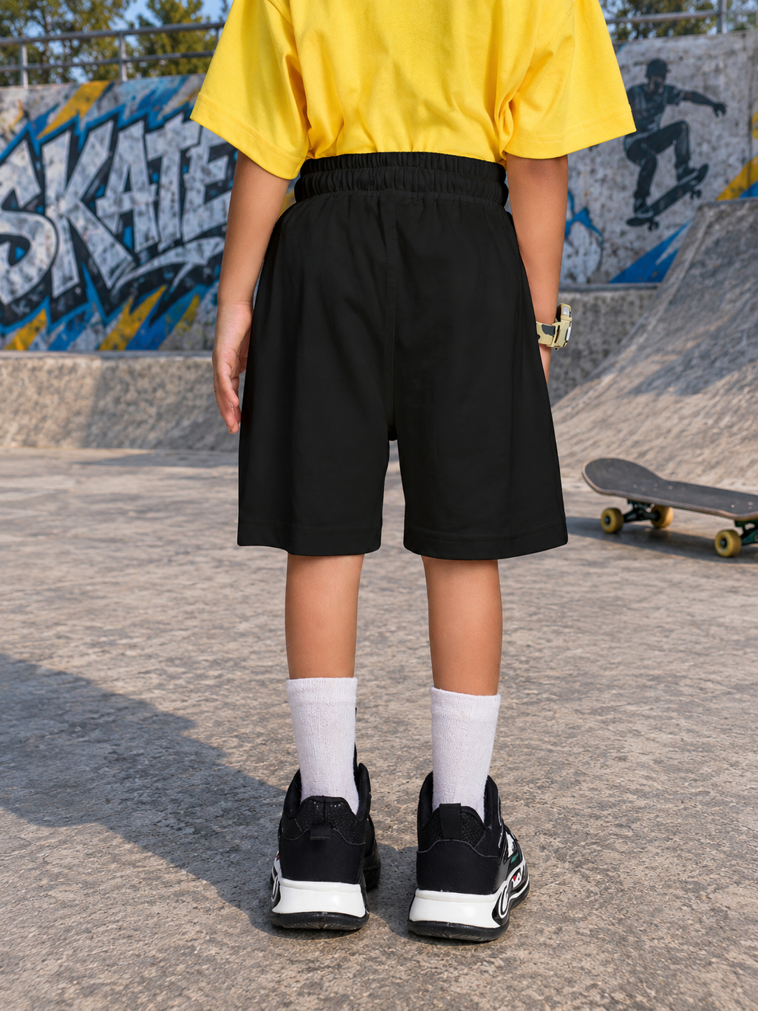 COOL DUDE SKATER CO-ORD FOR BOYS GIRLS BLACK YELLOW BLACK shown on a child at a skate park with a black shirt and yellow shorts.