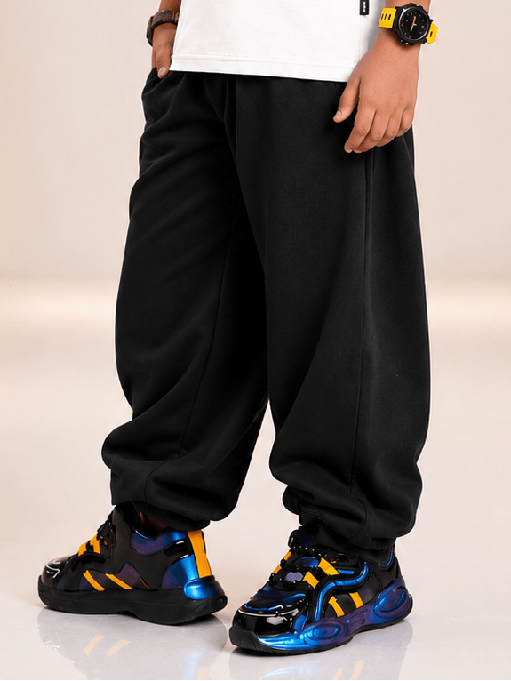 COOLFIT JOGGER FOR BOYS GIRLS BLACK worn by a kid, showcasing stylish black joggers and sporty sneakers.