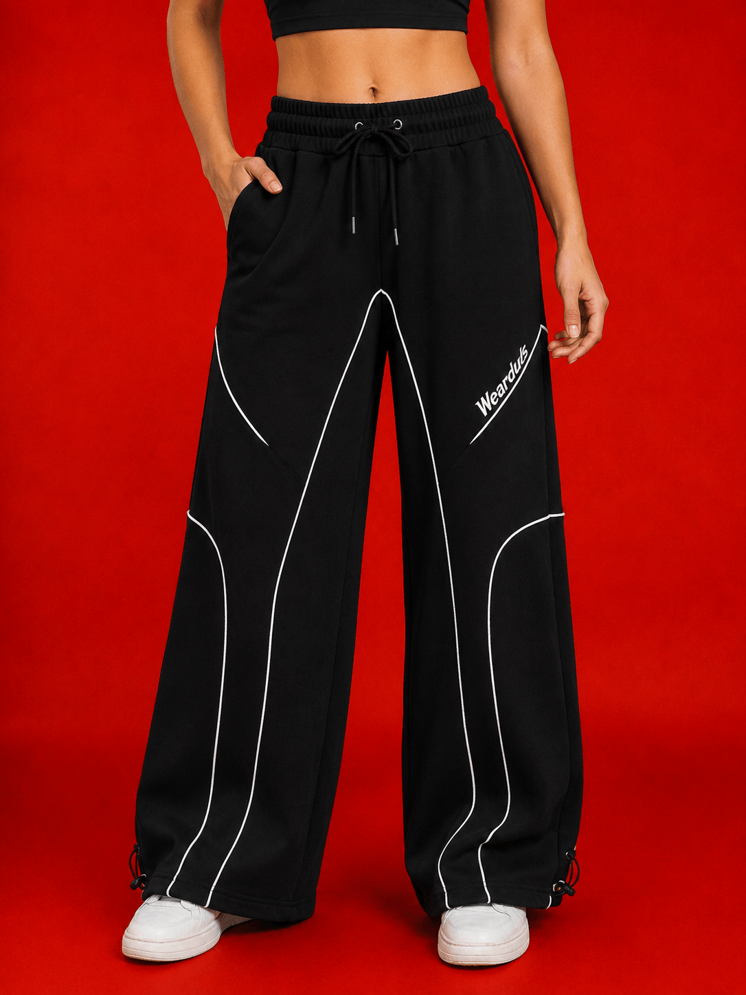 WOMEN SIGNATURE PIPING JOGGERS BLACK with contrast piping detail against a red background.