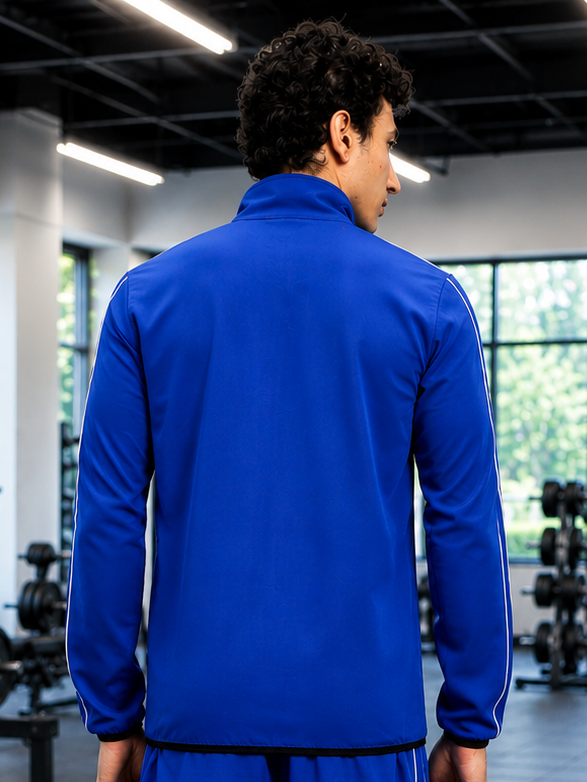 Back view of a model wearing the RELIGHT RELAXED FIT JACKET BLUE in a gym setting.