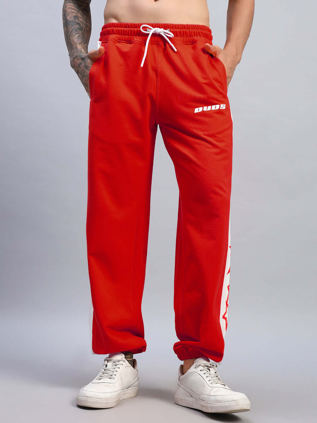 Model wearing red-white DUDS FLASH Relaxed Fit Joggers with drawstring waist, displaying sports-luxe style.