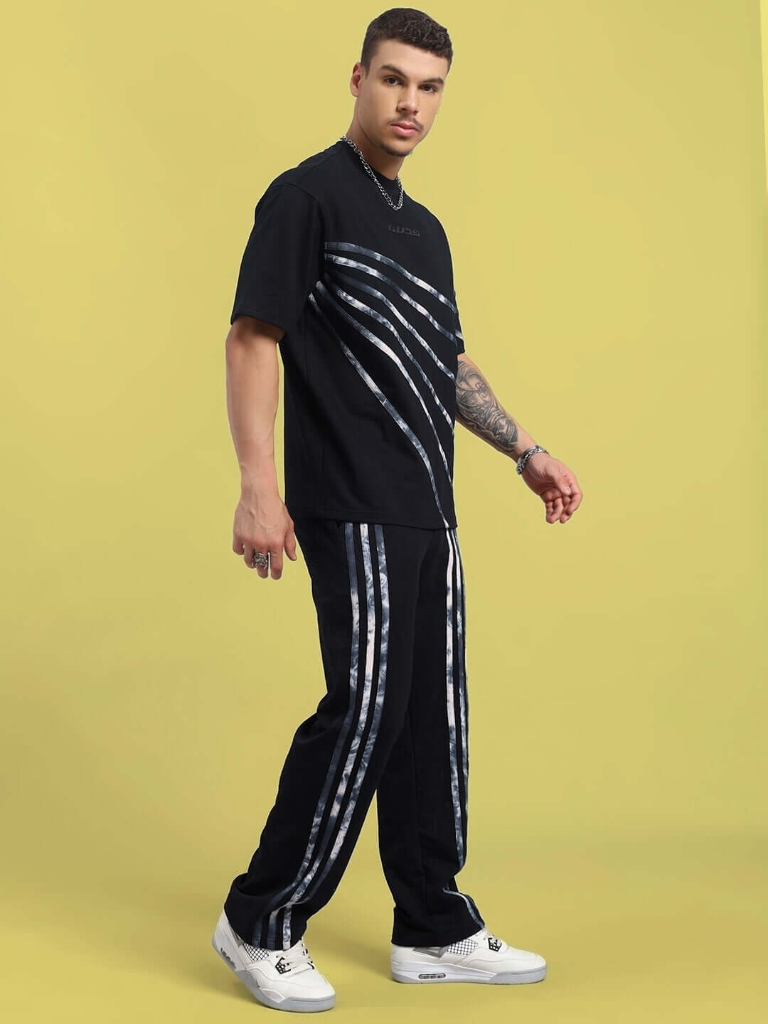Model wearing Flicker Oversized Co-Ord Set in black with unisex relaxed fit joggers and elasticated waistband against a yellow background.