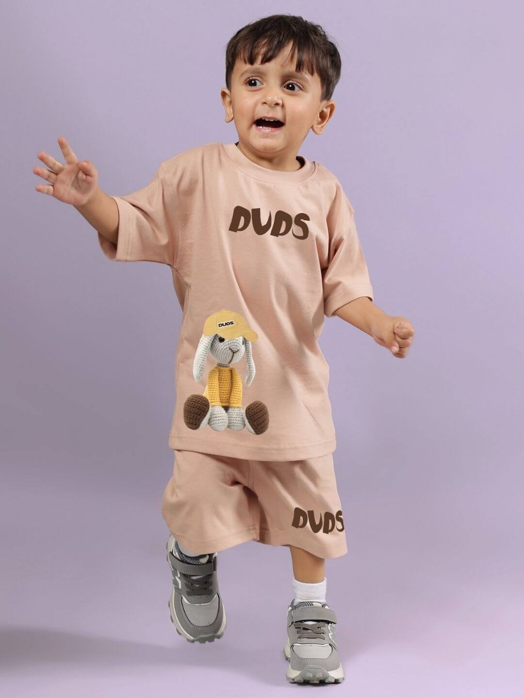 Alt Tag: Child wearing FLINT BUNNY CO-ORD FOR BOYS AND GIRLS BEIGE, playful and stylish outfit, with bunny design, on purple background.