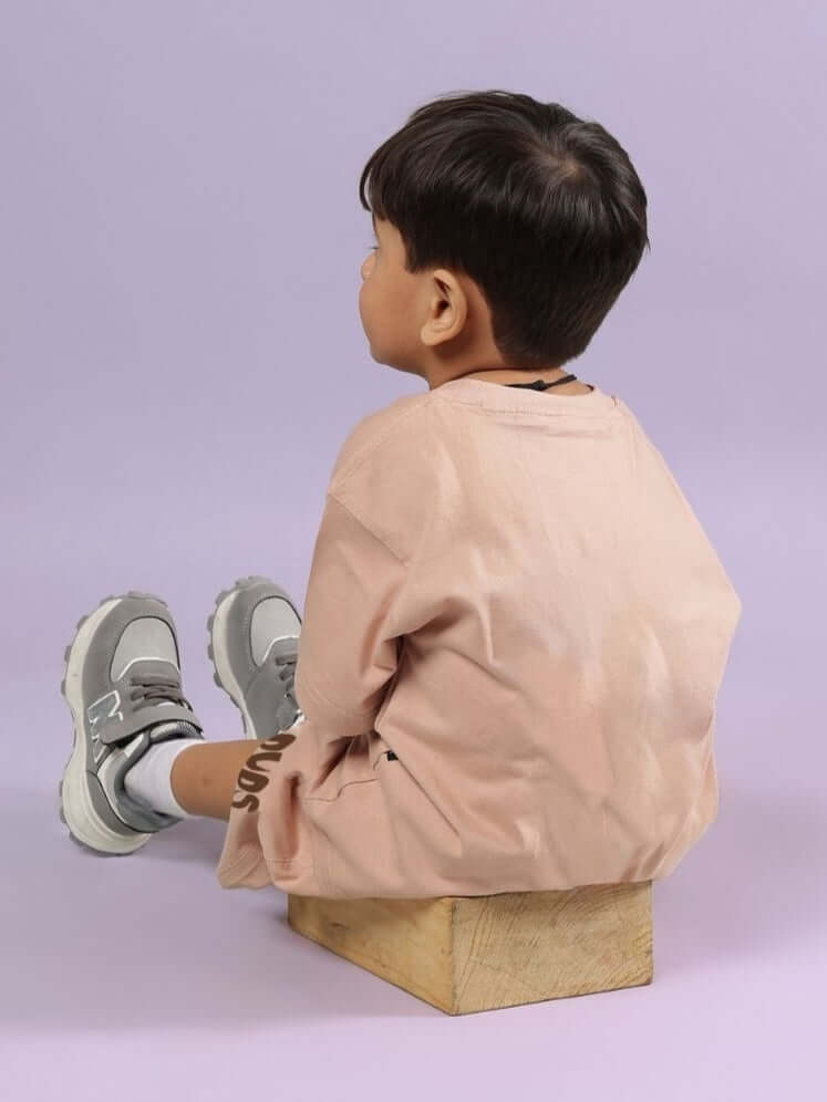Child wearing beige Flint Bunny co-ord set, sitting on a wooden block, showcasing a unisex outfit for boys and girls.