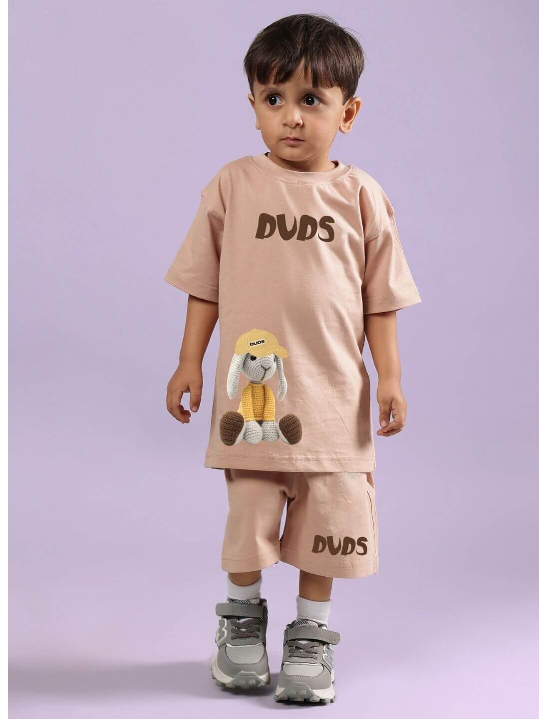 Child in beige Flint Bunny co-ord set with bunny design, soft pastel background.