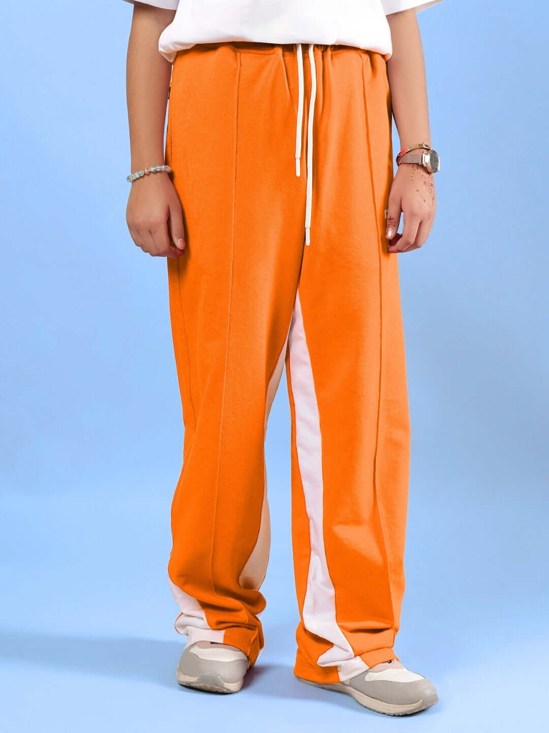 Person wearing FLOPPY JOGGER FOR BOYS & GIRLS ORANGE with white stripes, standing against a blue background.