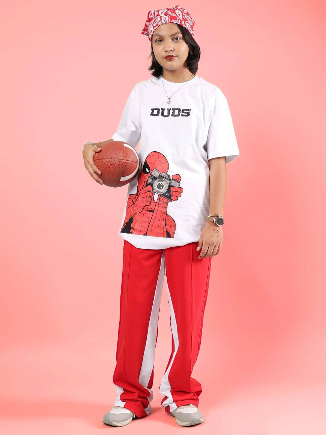Young person wearing DUDS floppy jogger in red, holding a basketball, styled for boys and girls. Customizable fit option available.