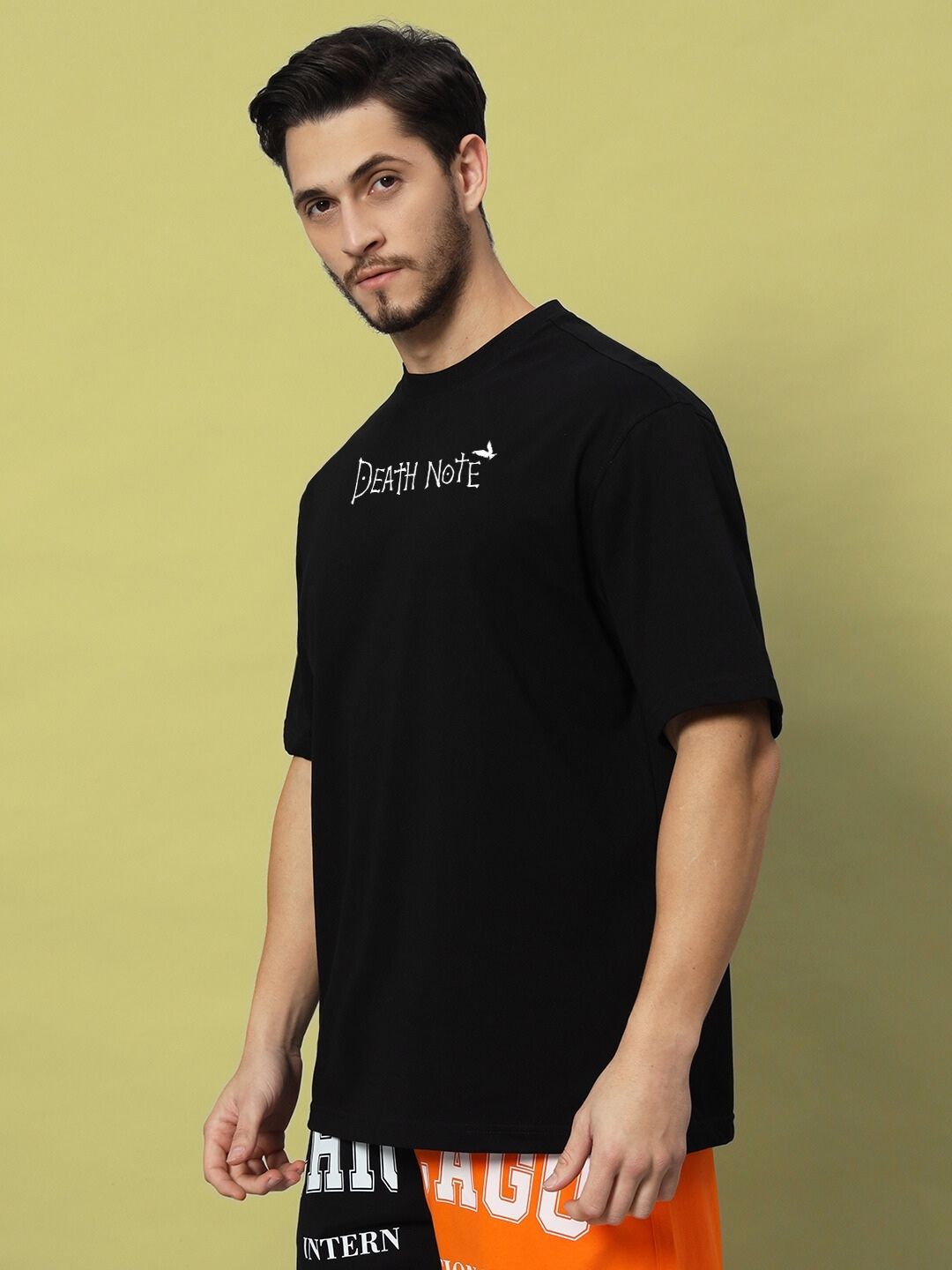 Man wearing FOLLOW LIFE OVERSIZED T-SHIRT BLACK, featuring Death Note design, standing against a neutral background.
