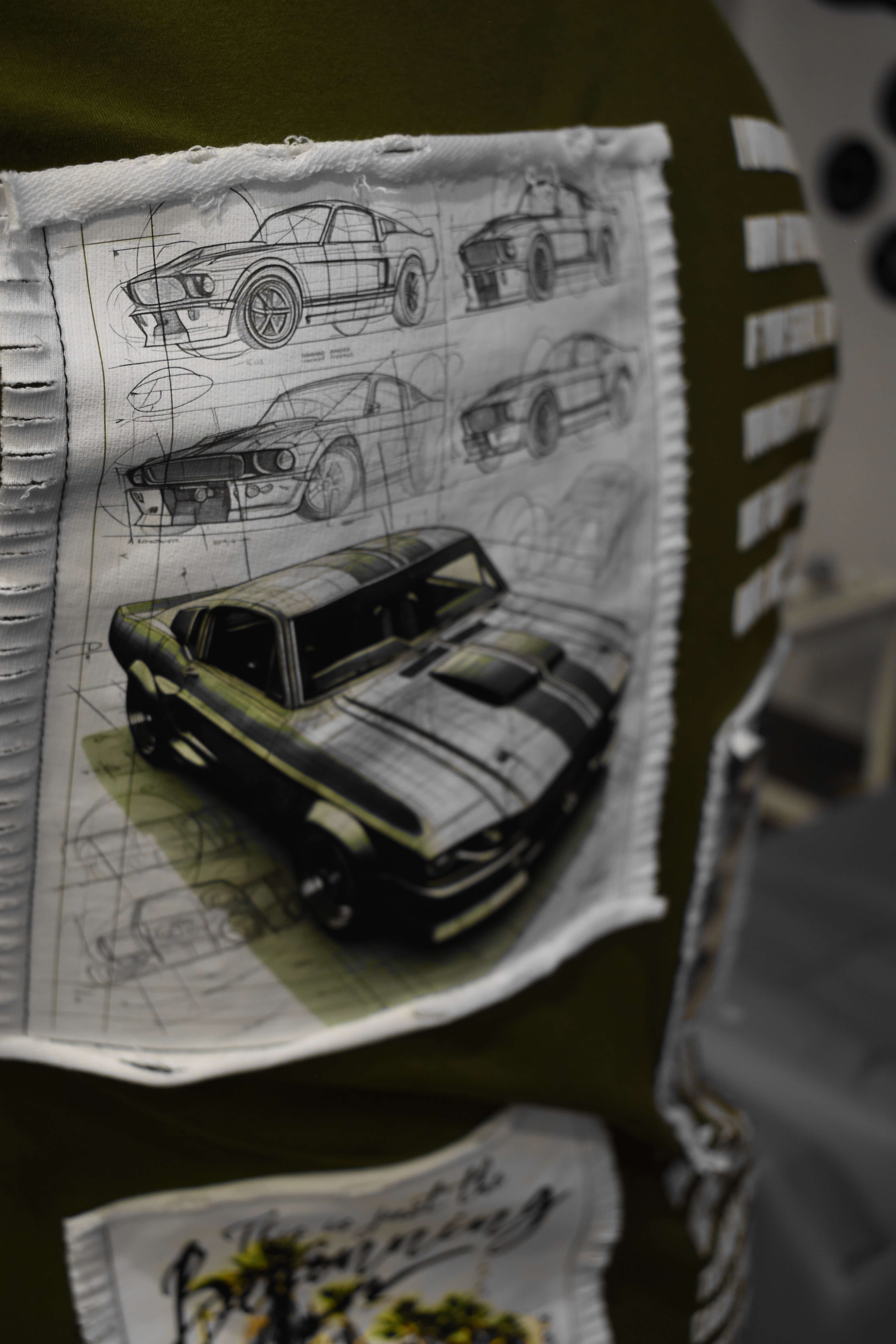 Olive green oversized t-shirt with Ford Mustang design, featuring detailed car sketches. Made from premium cotton and elastane blend.