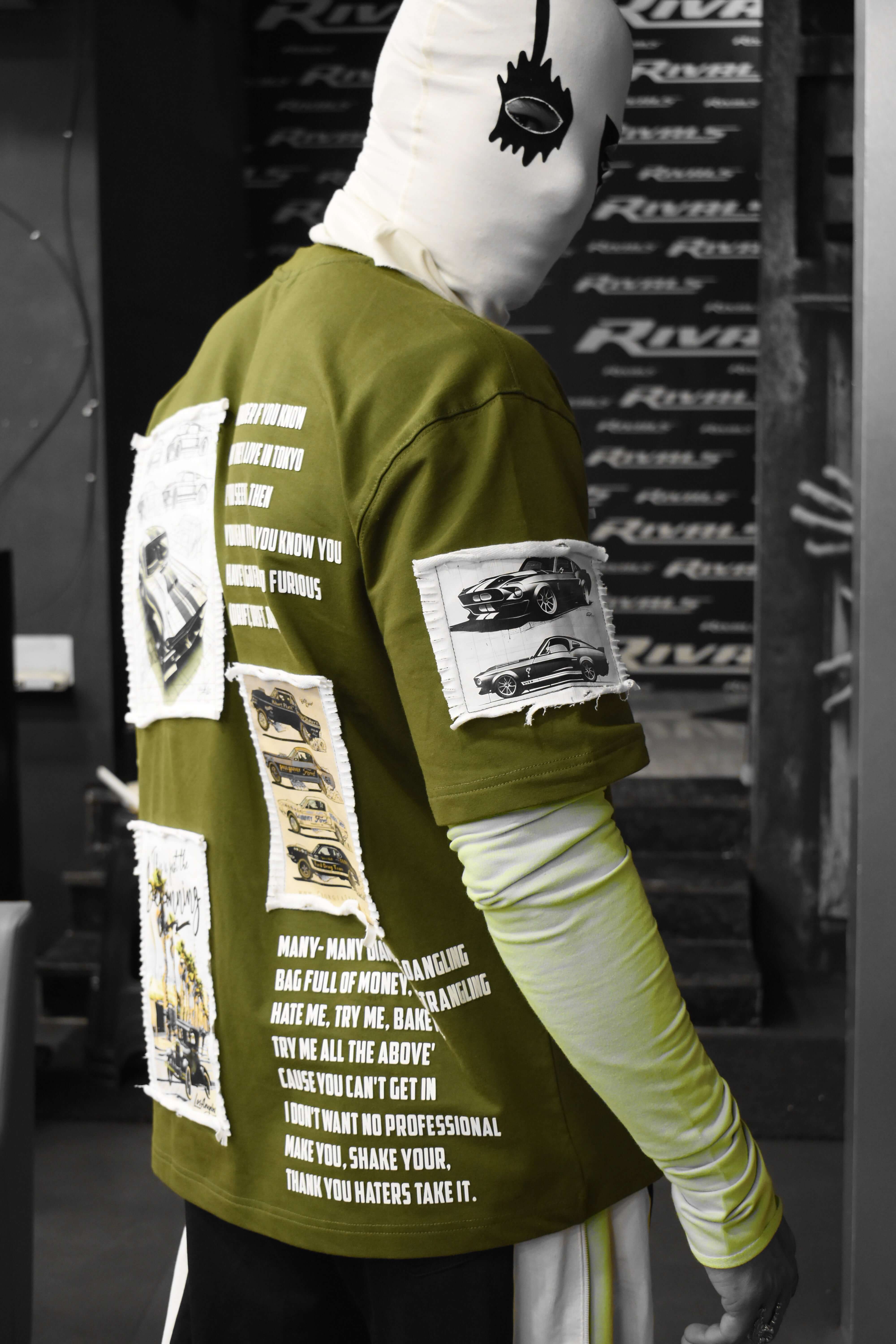 Olive green oversized Ford Mustang designer t-shirt featuring vintage car prints and streetwear style patches.