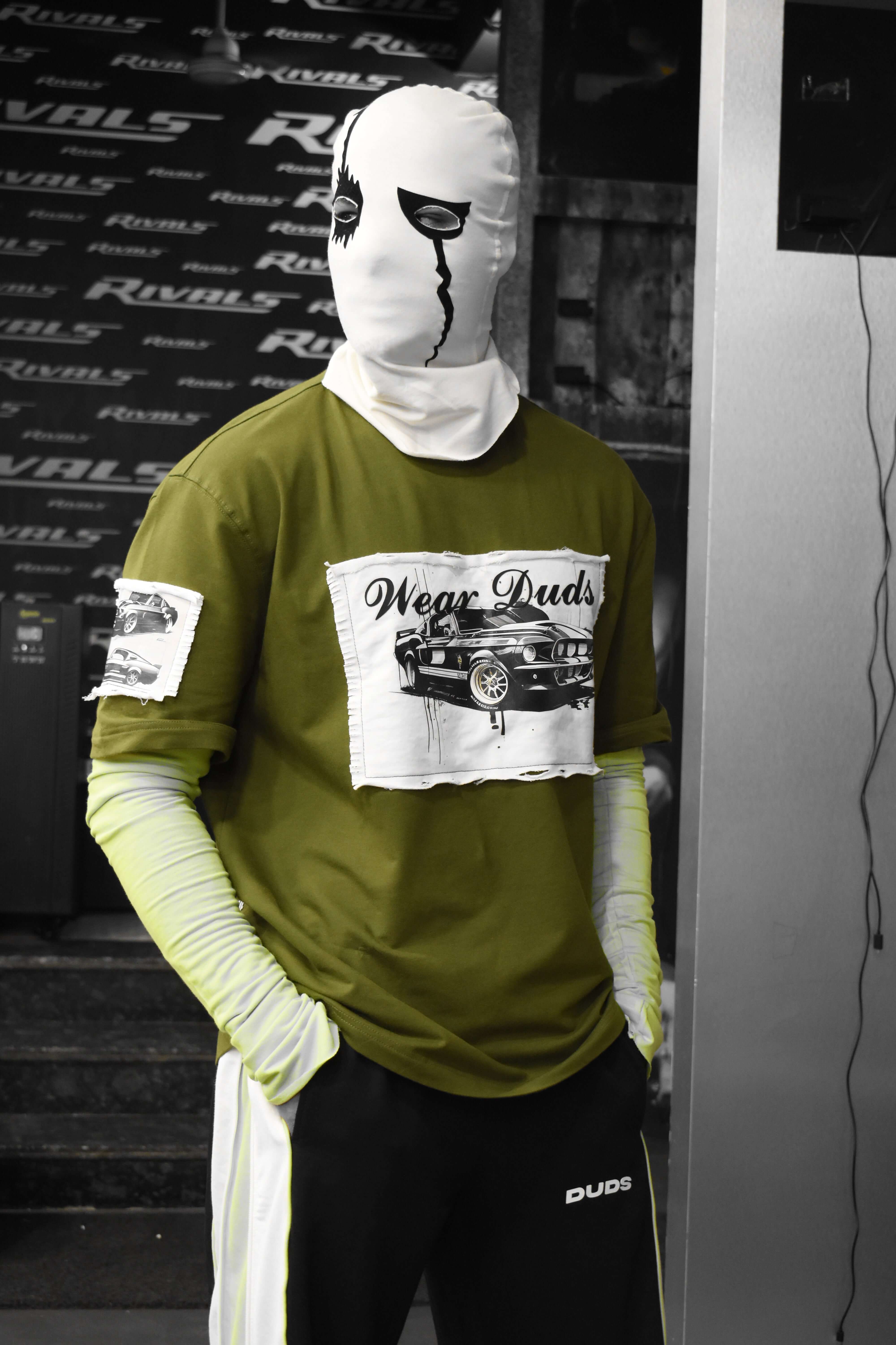 Model in olive green Ford Mustang designer oversized t-shirt with unique mask, showcasing premium heavy gauge fabric.