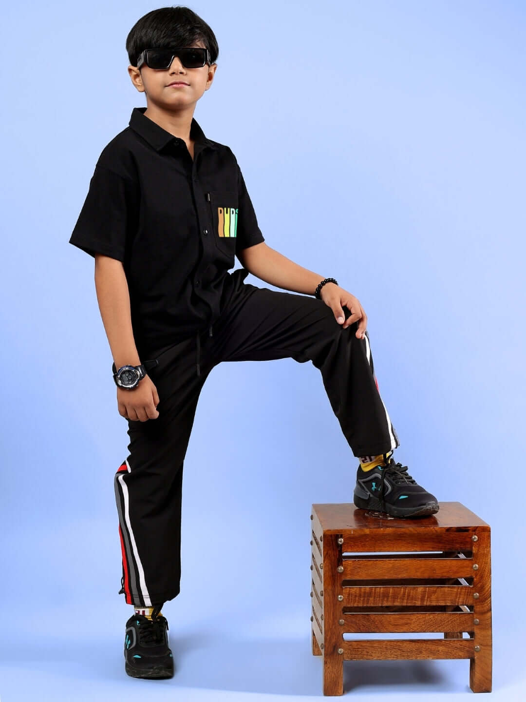 Child wearing FOREVER GAMER co-ord set in black, standing with one foot on stool, showcasing comfortable and stylish outfit for kids.