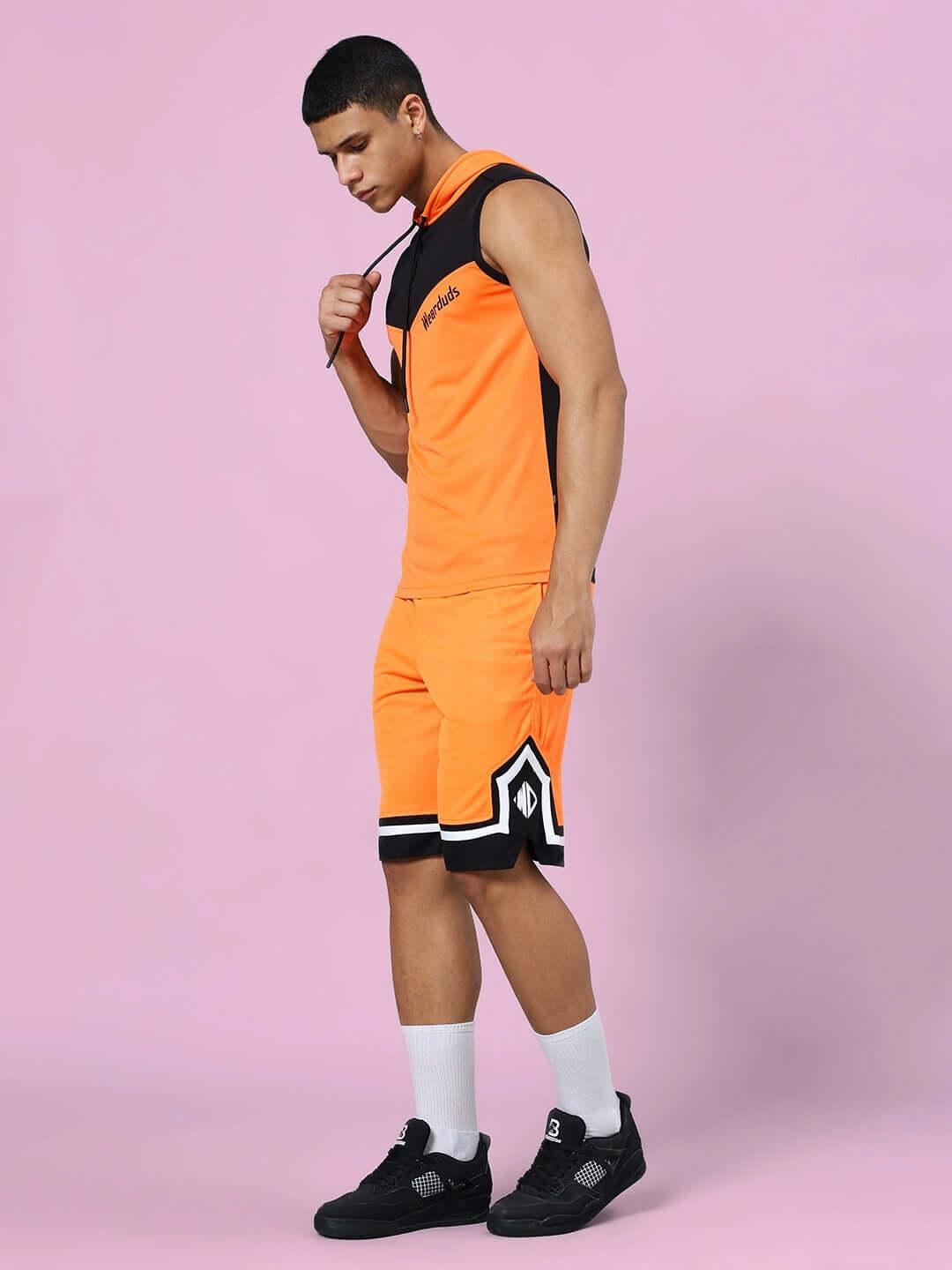 Model wearing FRANKY GYM CO-ORD SET ORANGE BLACK showcasing sports polyester fabric against a pink background.