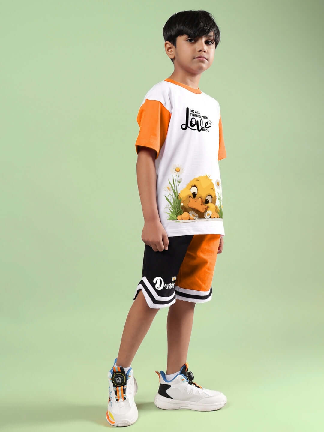 FRIENDSHIP BUCKET CO-ORD FOR BOYS & GIRLS WHITE ORANGE outfit modeled by child, featuring playful design with cartoon print, green background.