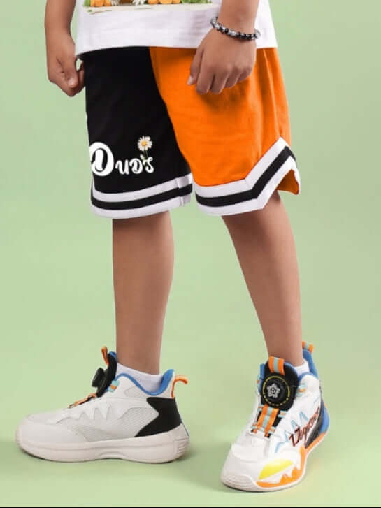 FRIENDSHIP BUCKET SHORTS FOR BOYS & GIRLS BLACK-ORANGE worn by a child, featuring white sneakers and colorful details.
