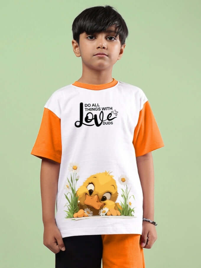 Child wearing FRIENDSHIP BUCKET T-SHIRT FOR BOYS & GIRLS WHITE-ORANGE with cartoon duck design, green background