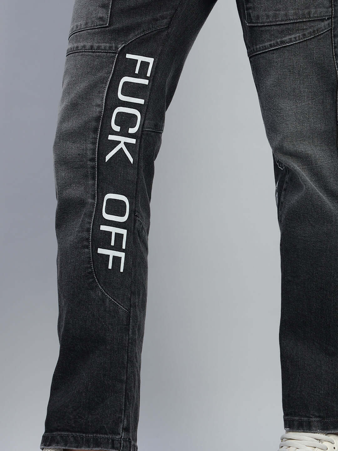 Close-up of black regular fit denim jeans with bold 'FUCK OFF' lettering, showcasing modern design and custom size options by DUDS.