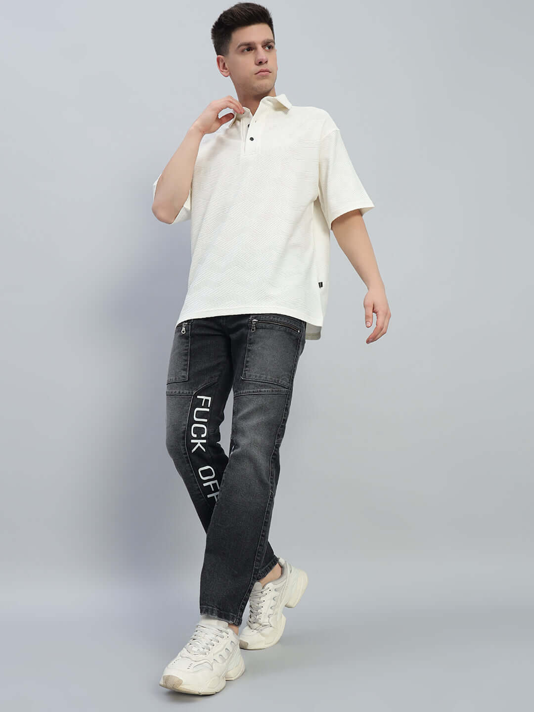 Model wearing 'FUCK OFF' regular fit black denim jeans, showcasing modern streetwear fashion style.