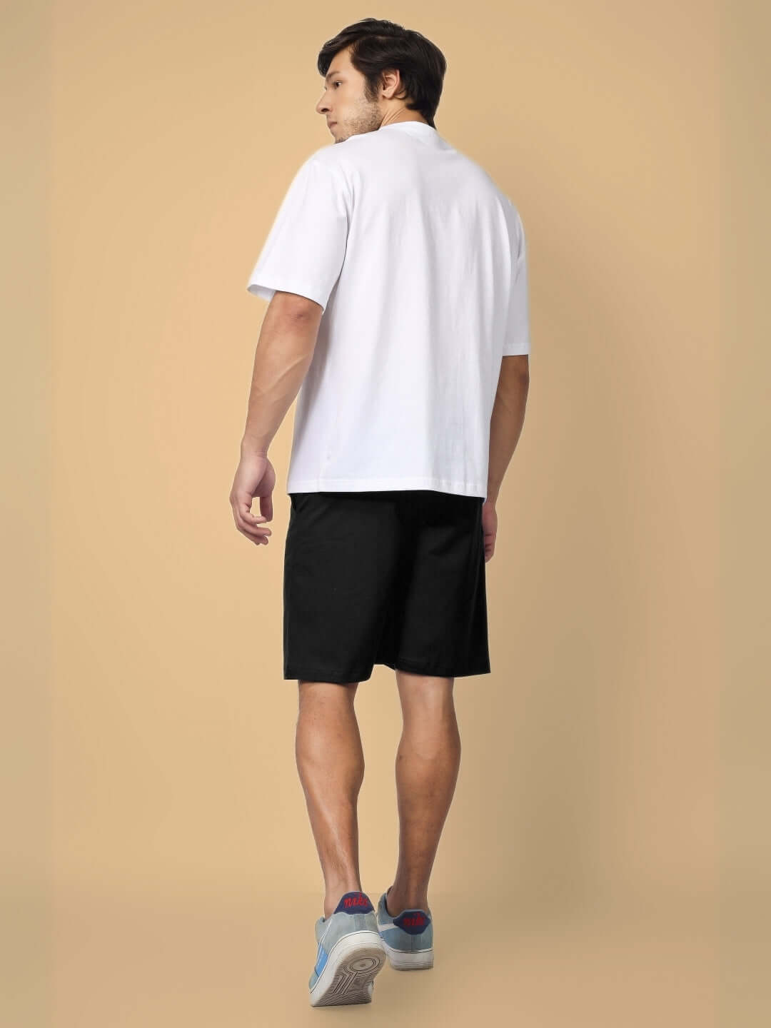 Man wearing FULNESS PARADISE CO-ORD SET WHITE BLACK with white top and black shorts, rear view.