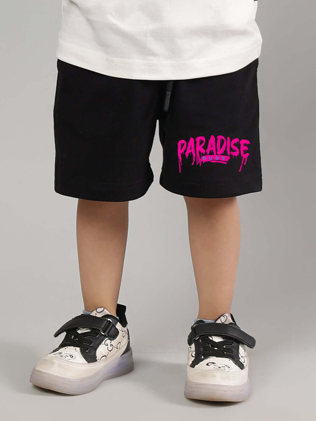 Alt Tag: Black summer shorts for boys and girls with pink "Paradise" print, worn by child, designed by DUDS, customizable fit.