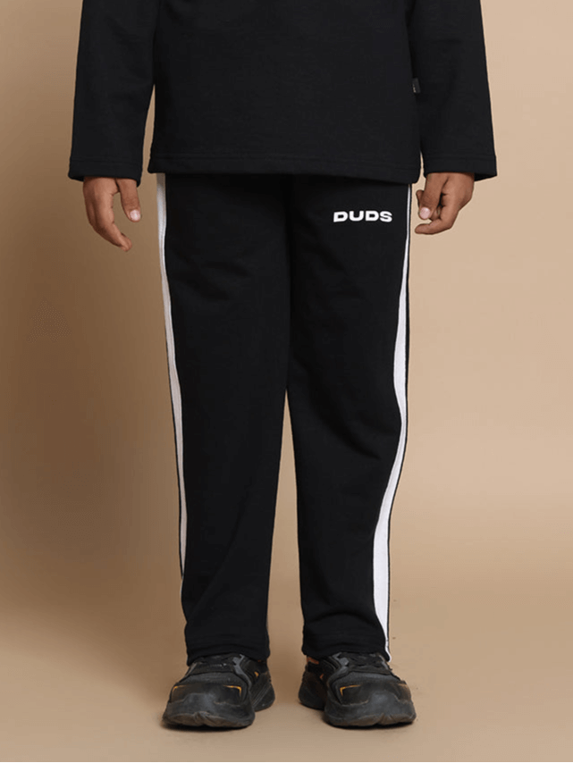 Young model wearing black FUN-BABE joggers with white stripes by DUDS, suitable for boys and girls, shown in a casual style.