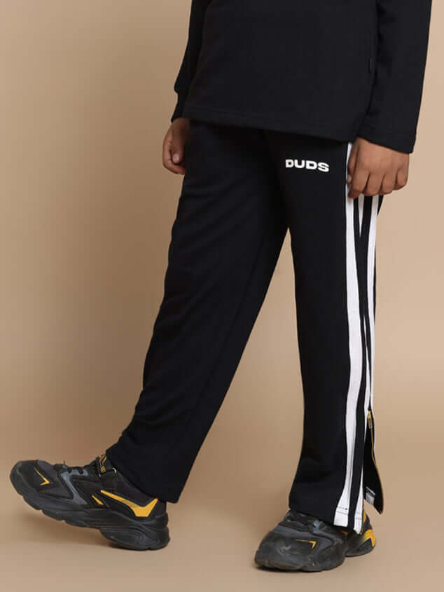 Child wearing black "FUN-BABE" joggers by DUDS, featuring white side stripes. Custom fit available. Made to order, 7-10 days dispatch.