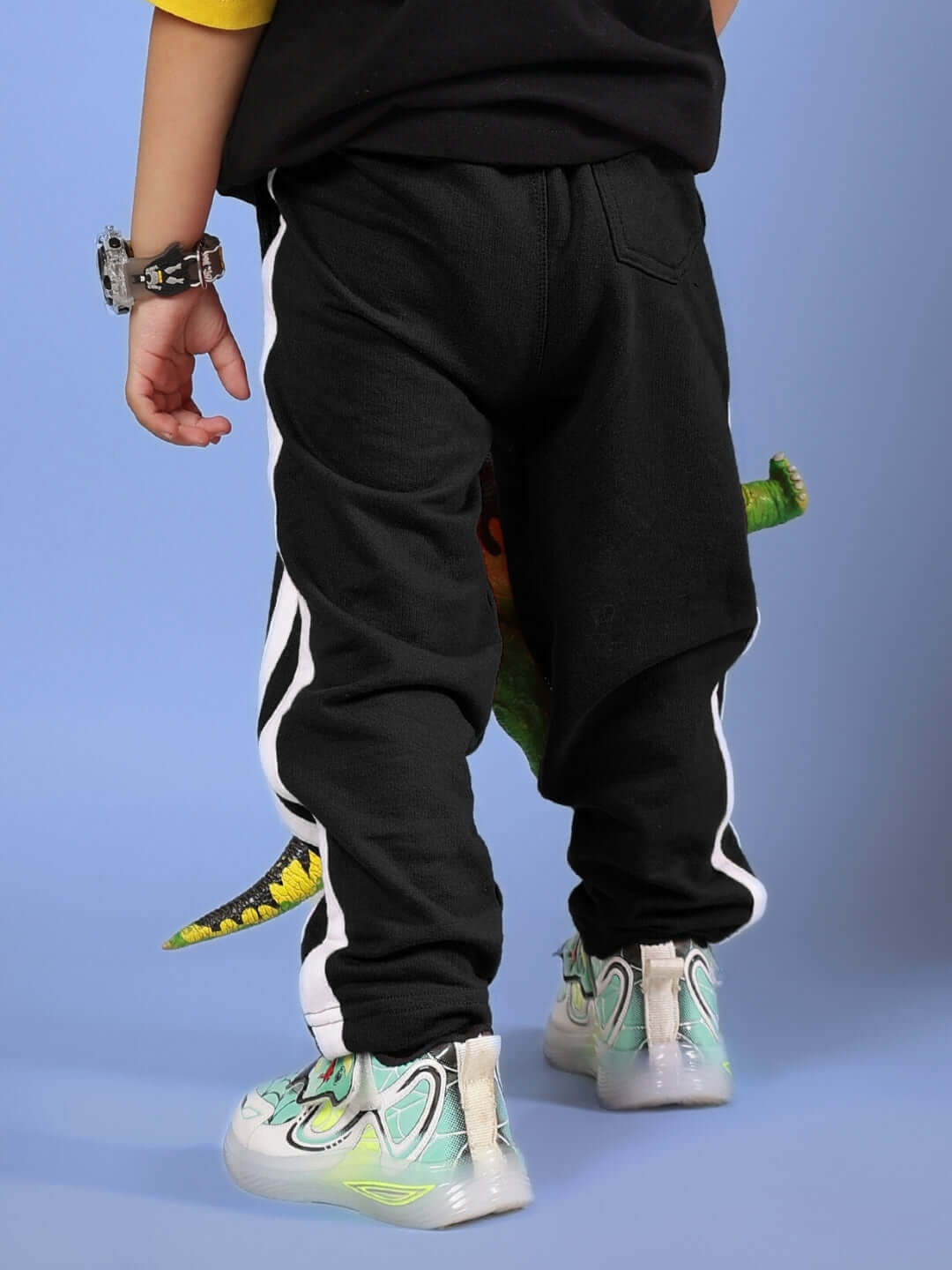 Child wearing FUTURE ICON JOGGER FOR BOYS & GIRLS BLACK with white stripes and stylish sneakers