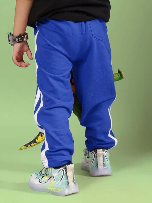 Child wearing FUTURE ICON JOGGER FOR BOYS & GIRLS BLUE standing against a green background.