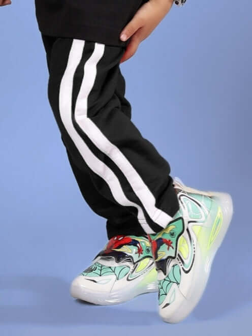 Child wearing FUTURE ICON JOGGER FOR BOYS & GIRLS BLACK with colorful sneakers, featuring white stripes.