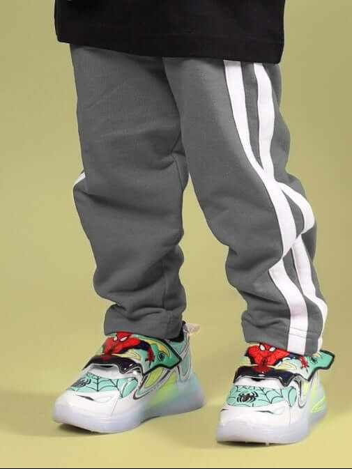 Grey jogger pants for boys and girls, featuring white stripes, displayed with colorful shoes on a child. Made by DUDS, customizable fit available.