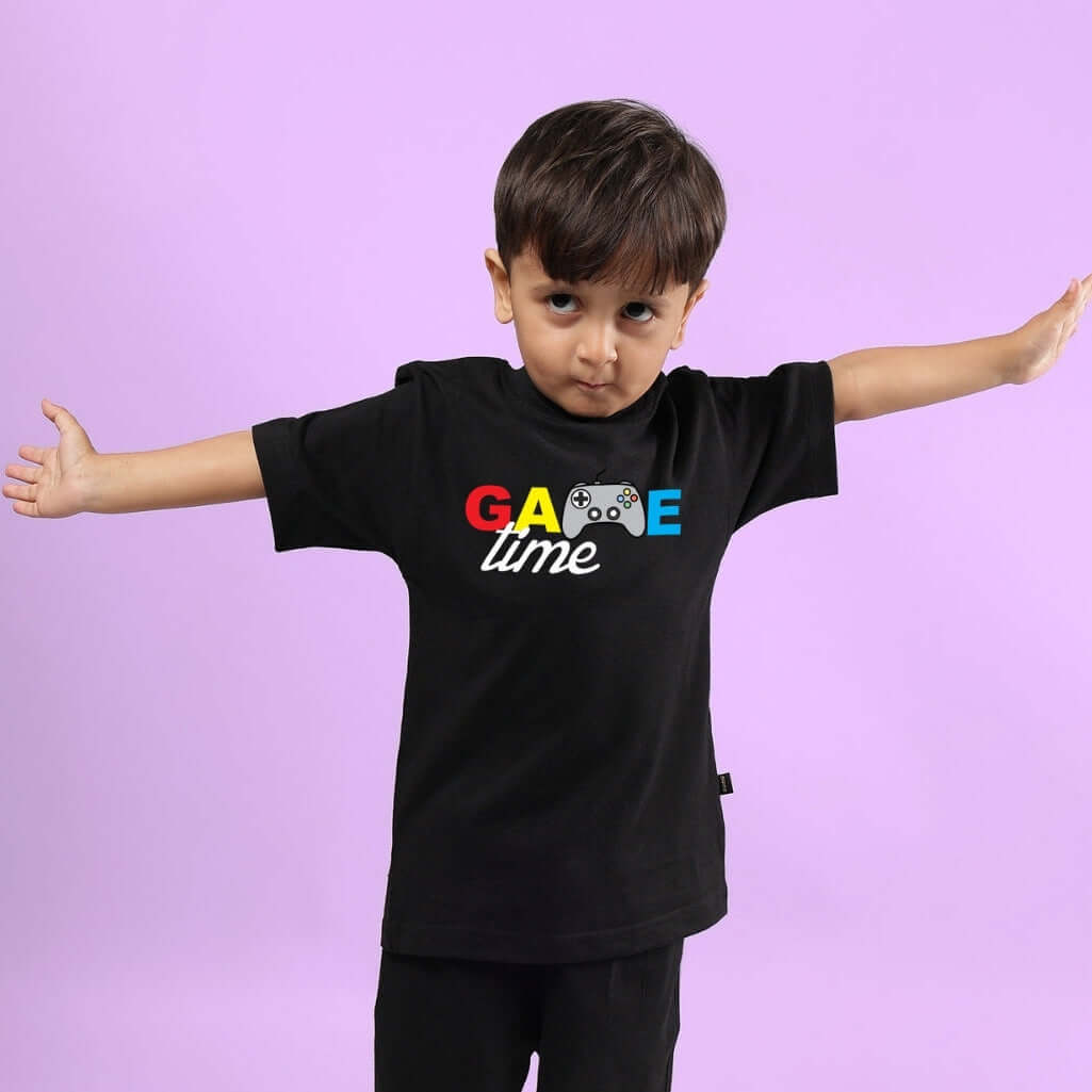 Child wearing GAME FINISHER T-SHIRT FOR BOYS & GIRLS BLACK, posing with arms outstretched, on a purple background.