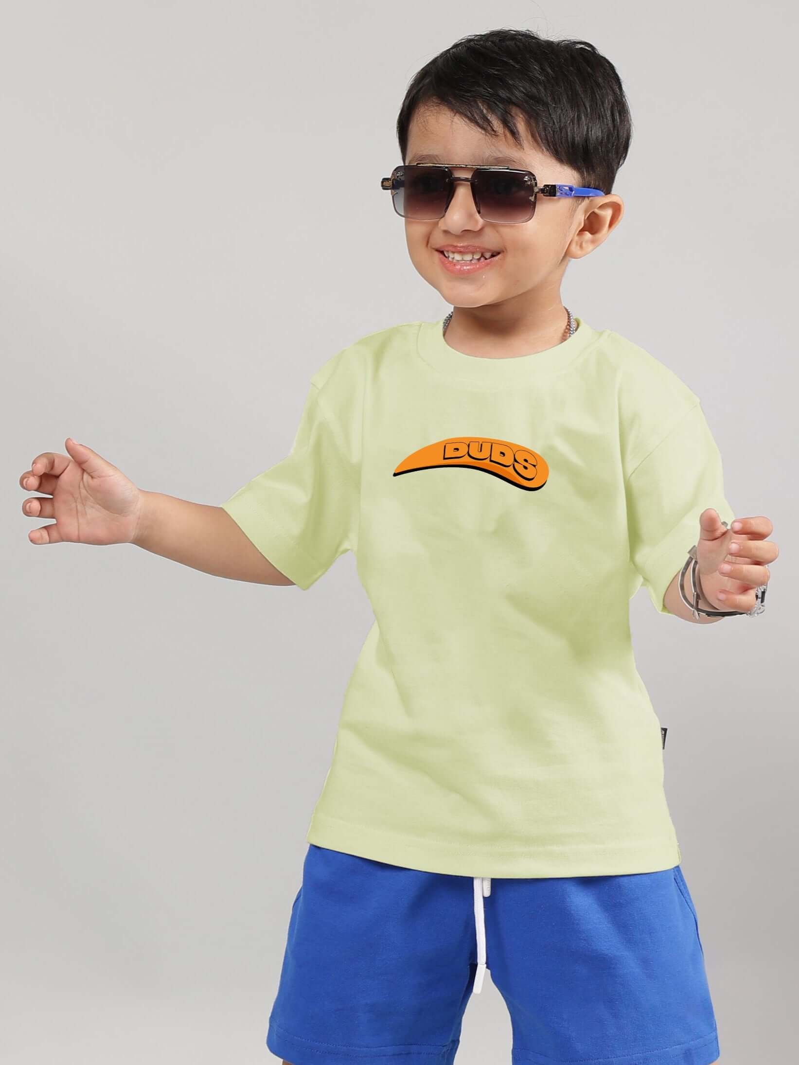 Boy wearing celery-ice Garfield T-shirt by DUDS, smiling in sunglasses with blue shorts.