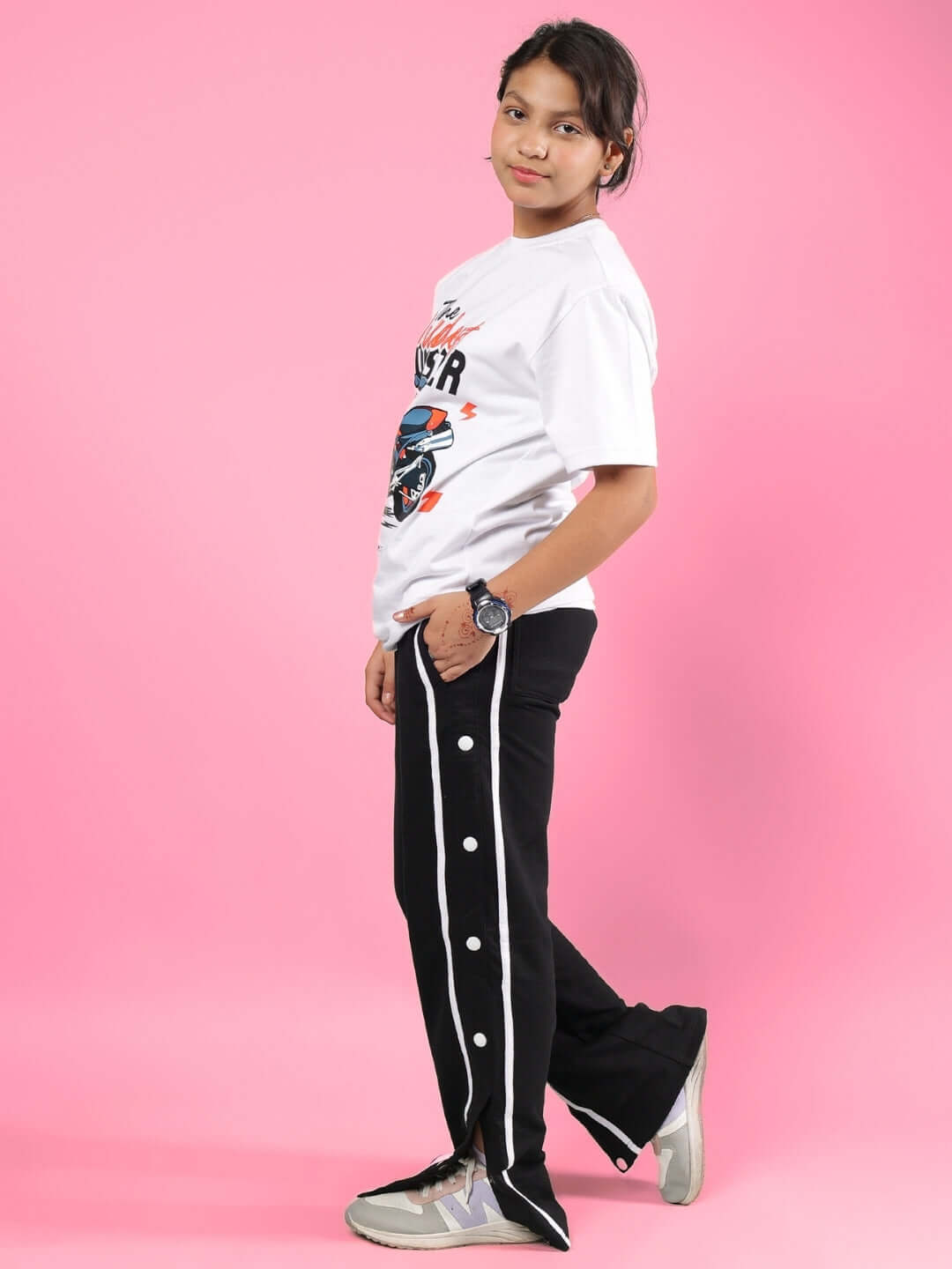 Child wearing GIXXER CO-ORD FOR BOYS & GIRLS WHITE-BLACK outfit, with white shirt and black pants, standing against pink background.