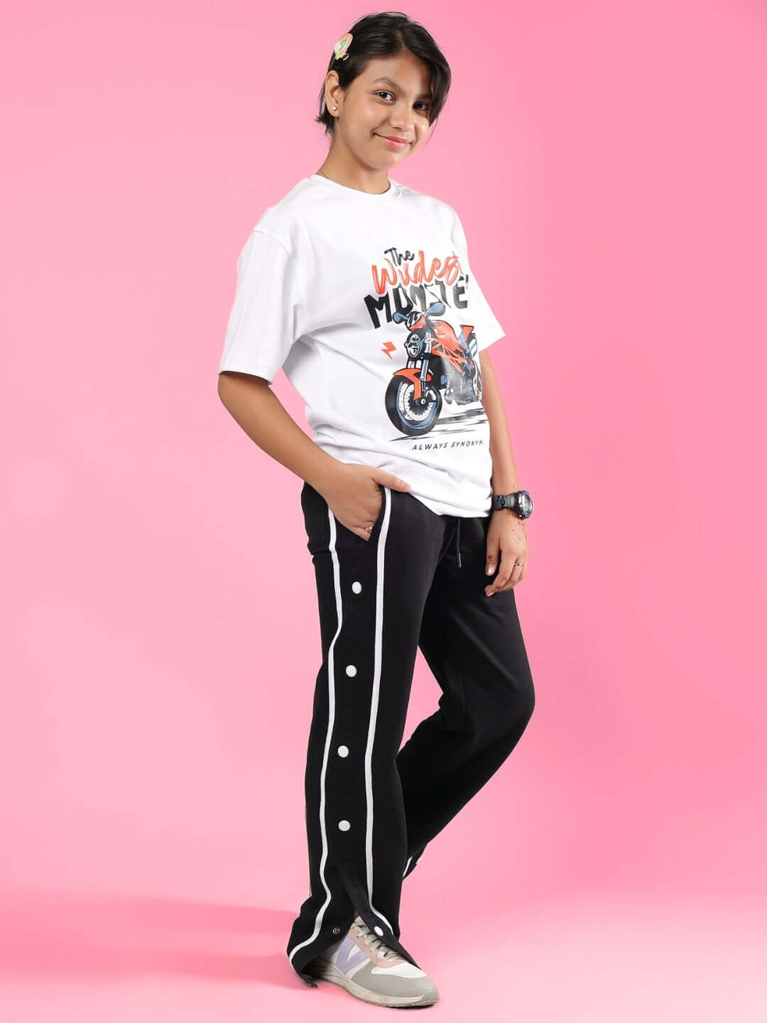 Child wearing GIXXER CO-ORD FOR BOYS & GIRLS WHITE-BLACK, featuring white t-shirt and black pants with button detail, against pink background.