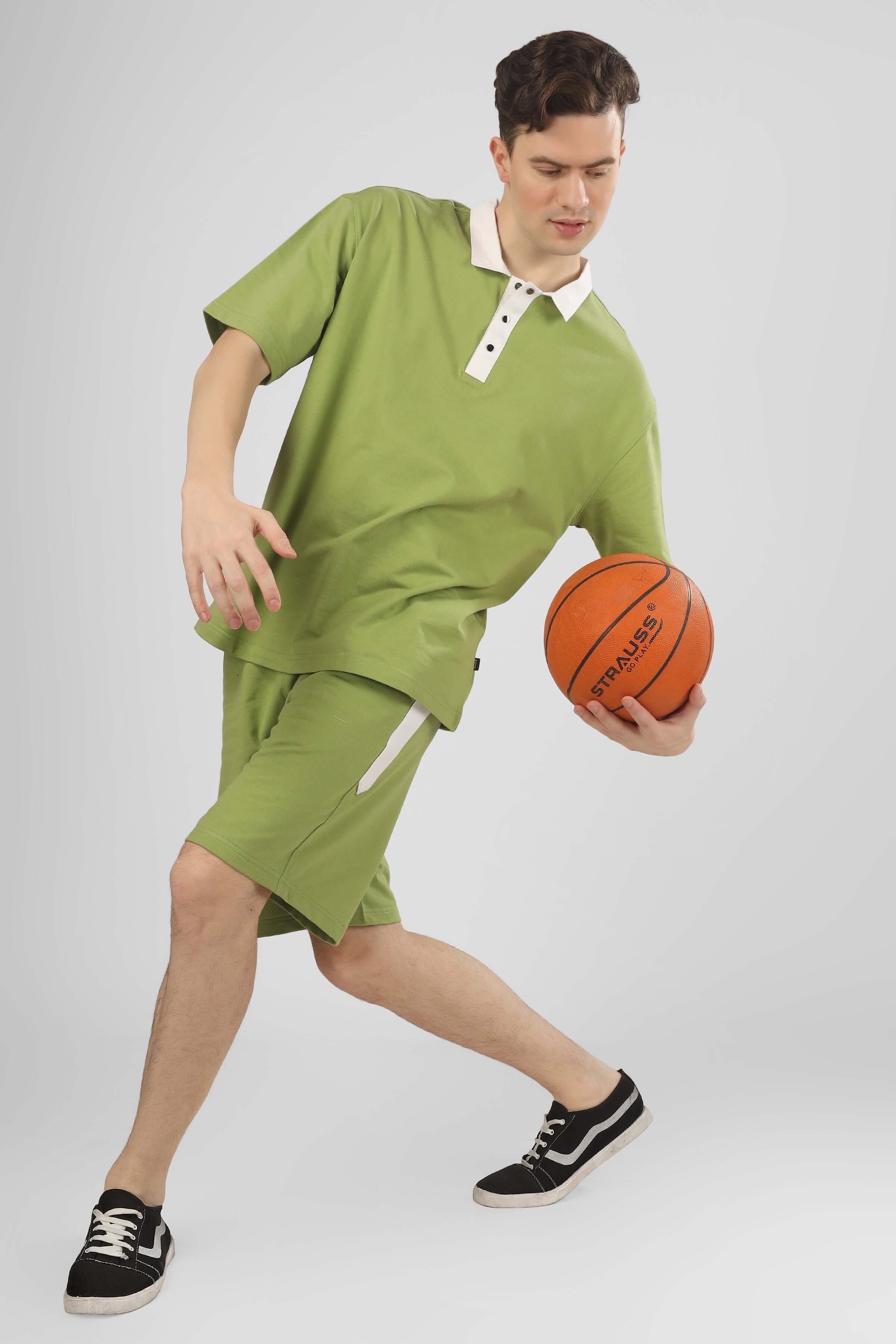 Man wearing GLAZY CO-ORD SET in pista green, playing with a basketball. Casual, sporty apparel made from premium cotton blend.