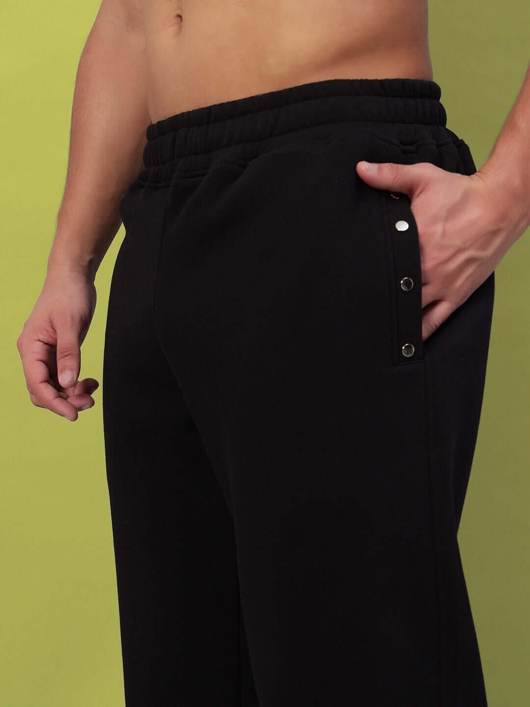 Close-up of black fleece joggers showcasing comfortable fit and stylish design with side button details.