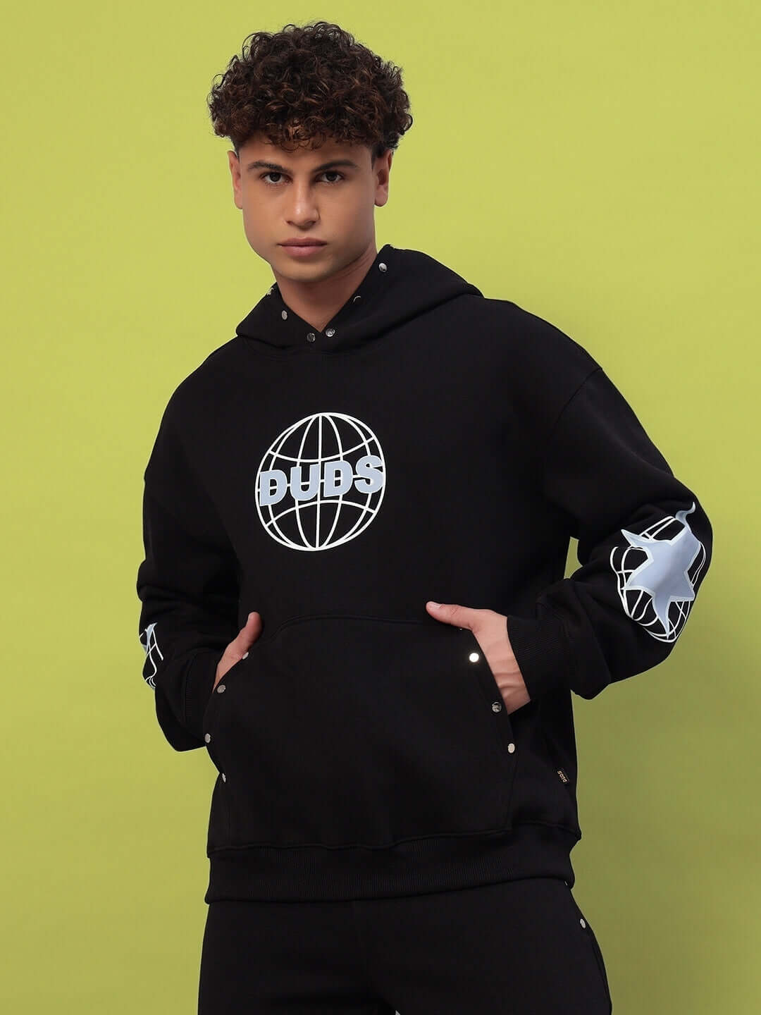 Man wearing GLOBAL COTTON FLEECE HOODIE BLACK with graphic design on front.
