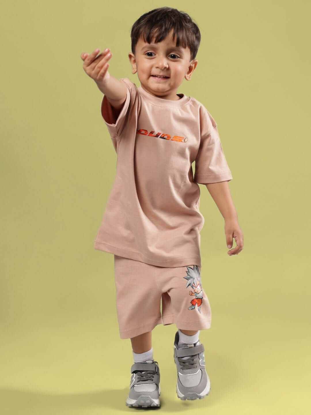 Child wearing GOHAN SHORTS FOR BOYS & GIRLS BEIGE with matching beige t-shirt on a light green background.
