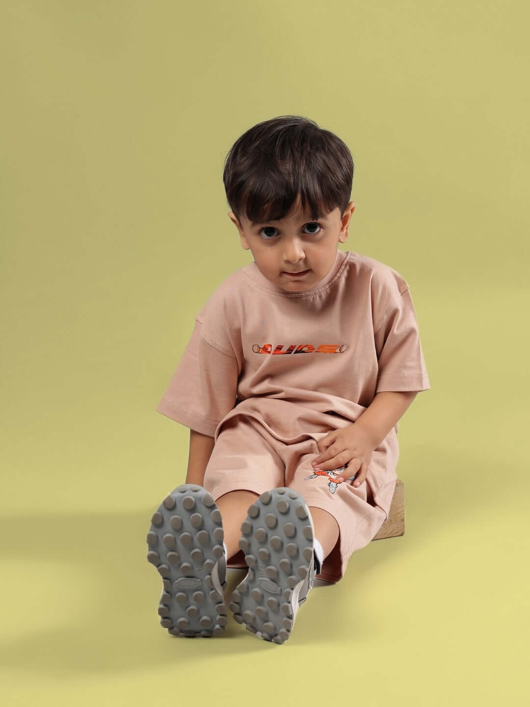 Child wearing GOHAN SUMMER CO-ORD FOR BOYS & GIRLS BEIGE set sitting on yellow background.