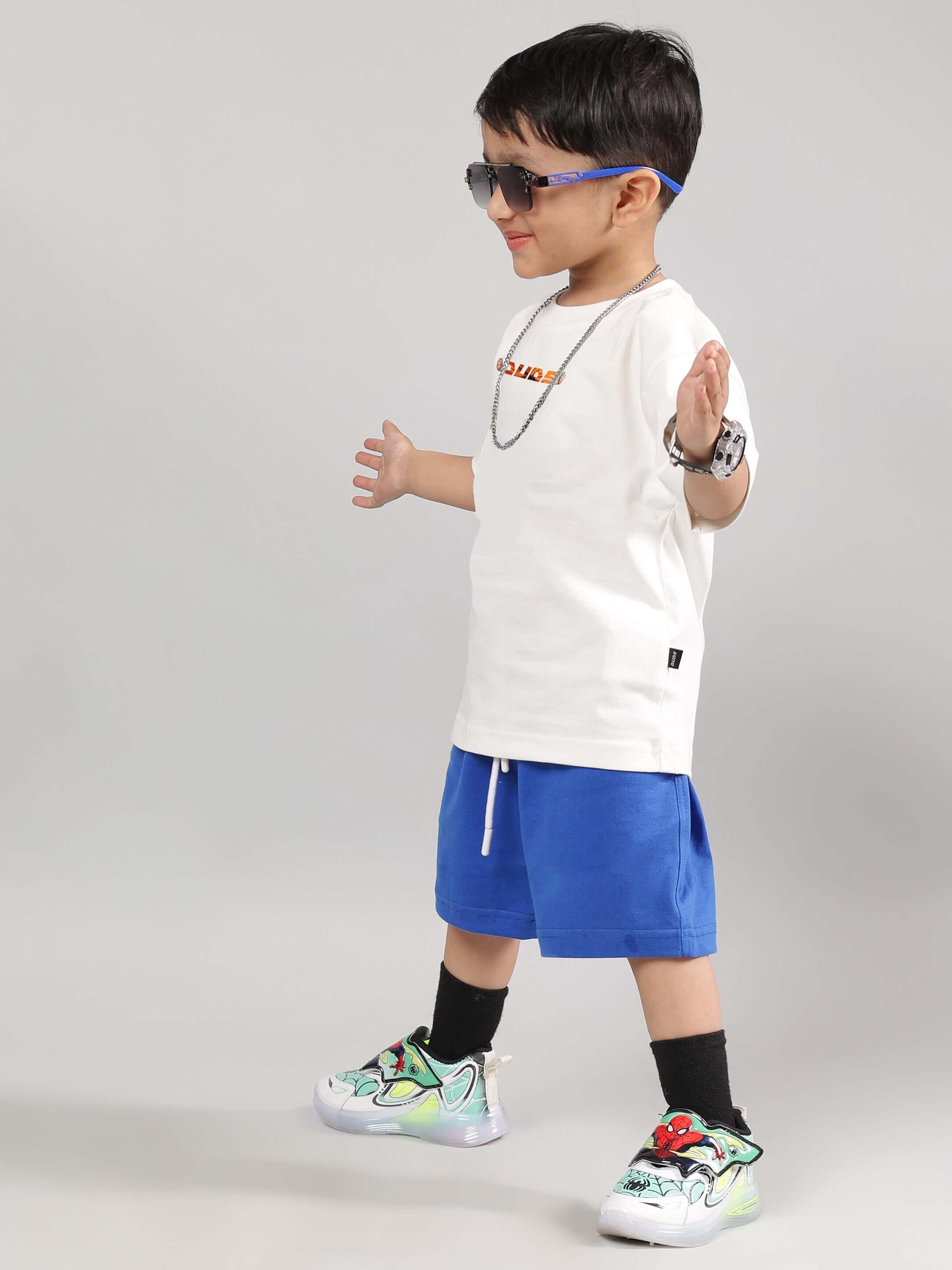 Child wearing GOHAN SUMMER CO-ORD FOR BOYS GIRLS OFF WHITE-BLUE with anime sneakers and sunglasses.