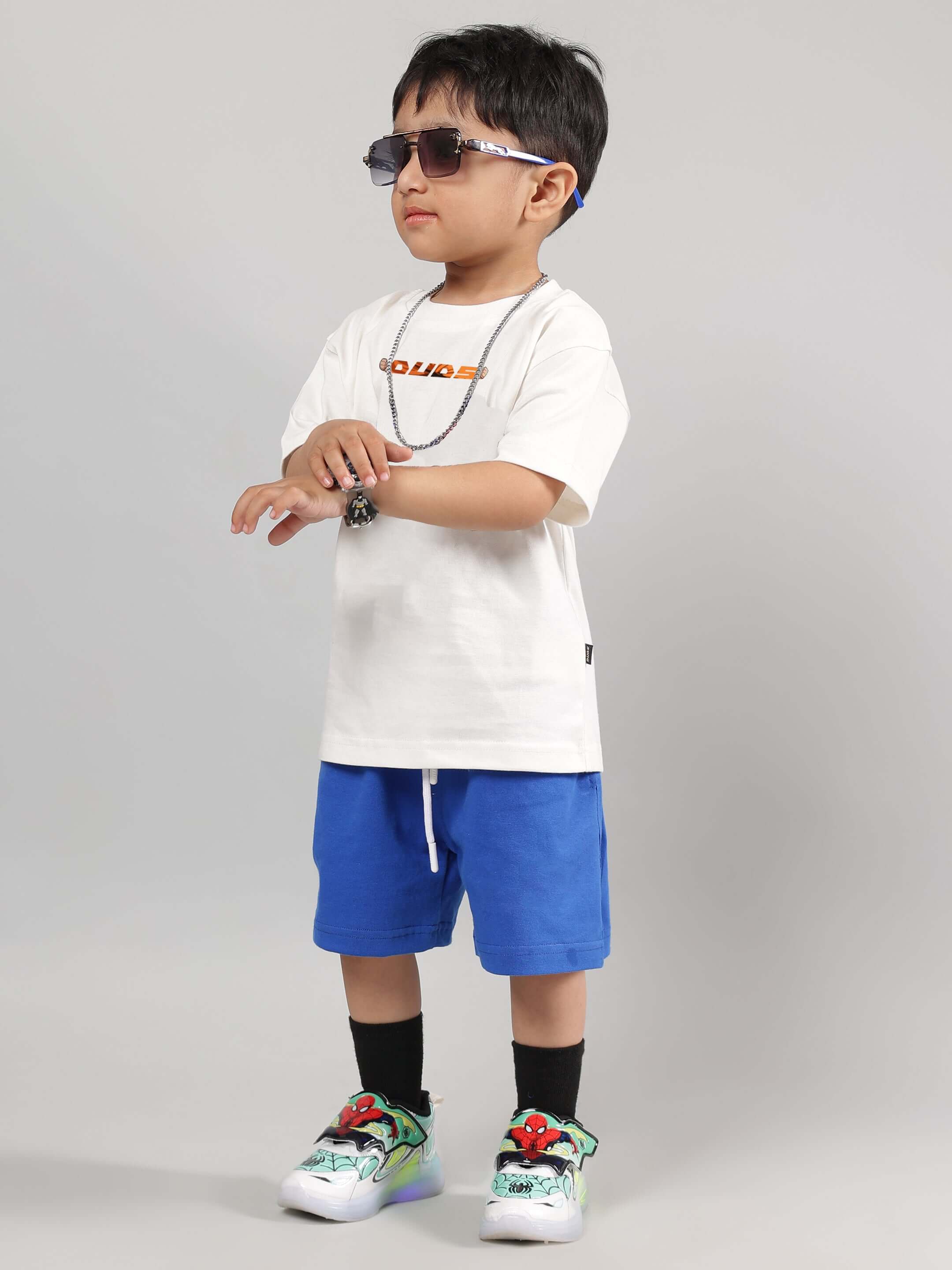 Child wearing off-white and blue GOHAN summer co-ord set with sunglasses and sneakers, showcasing stylish DUDS made-to-order outfit.