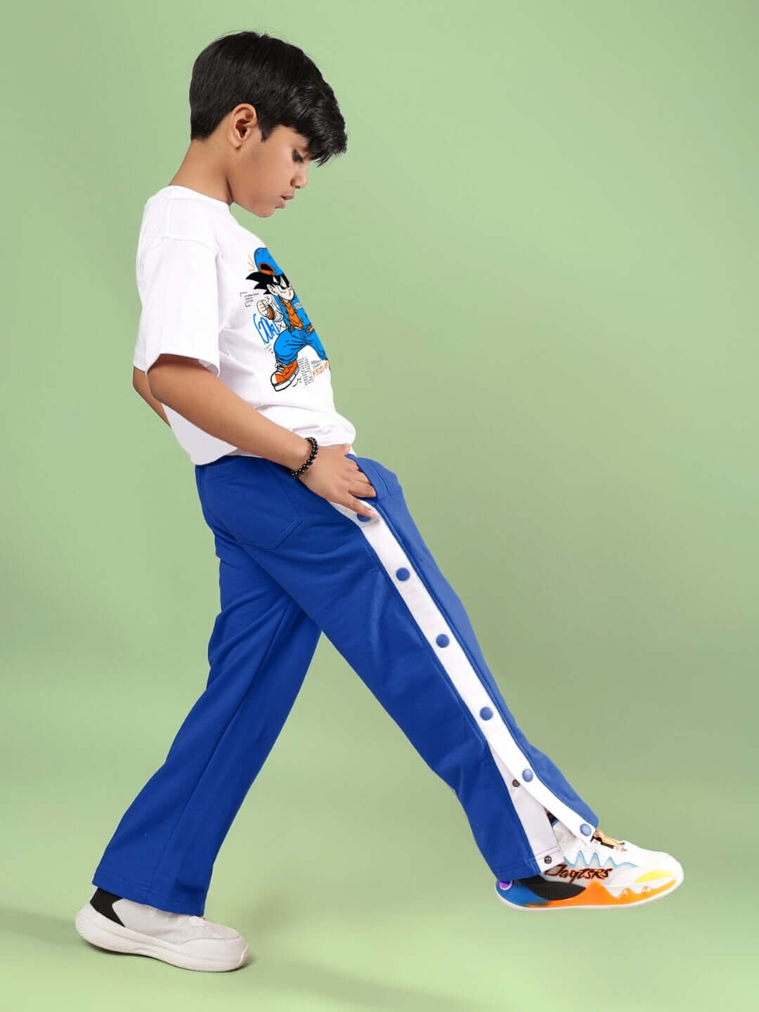 Boy wearing GOKU WARRIOR CO-ORD FOR BOYS & GIRLS WHITE BLUE standing sideways against green background