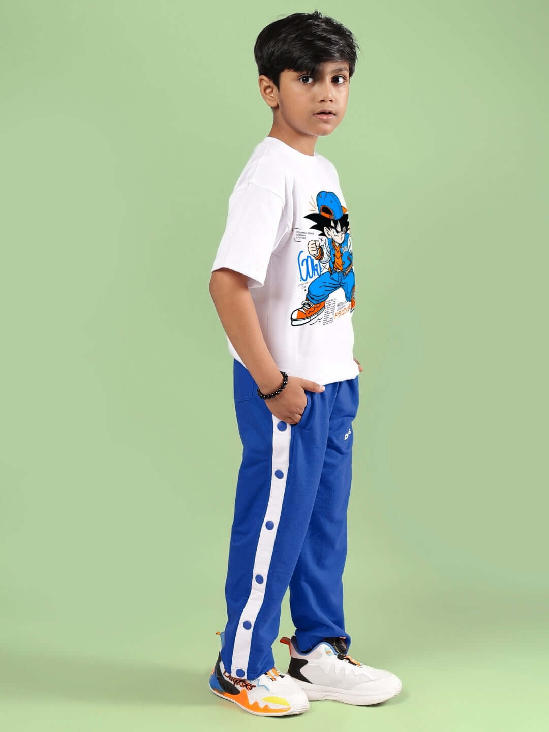 Young boy wearing GOKU WARRIOR CO-ORD FOR BOYS & GIRLS WHITE BLUE outfit standing against a green background.