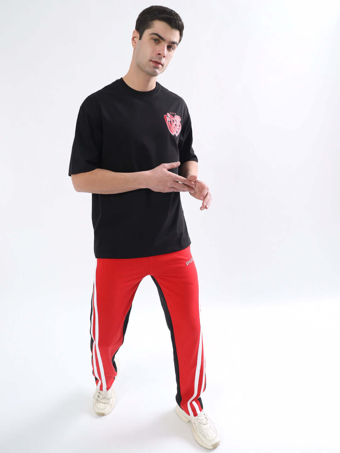 Model wearing black GOOD VIBES oversized t-shirt with red stripe pants, ideal for casual style. Custom fit available for prepaid orders.