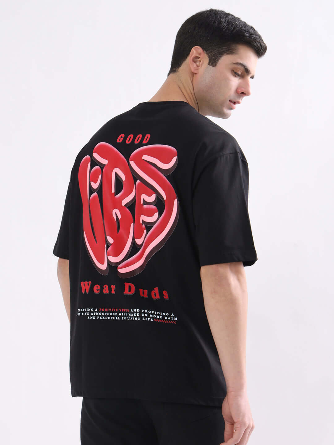 Man wearing GOOD VIBES oversized black T-shirt with red lettering by DUDS. Custom fit available for prepaid orders.