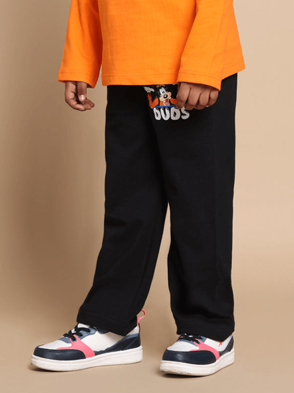 Child wearing black GOOFY joggers for boys & girls by DUDS, styled with casual shoes and an orange top.