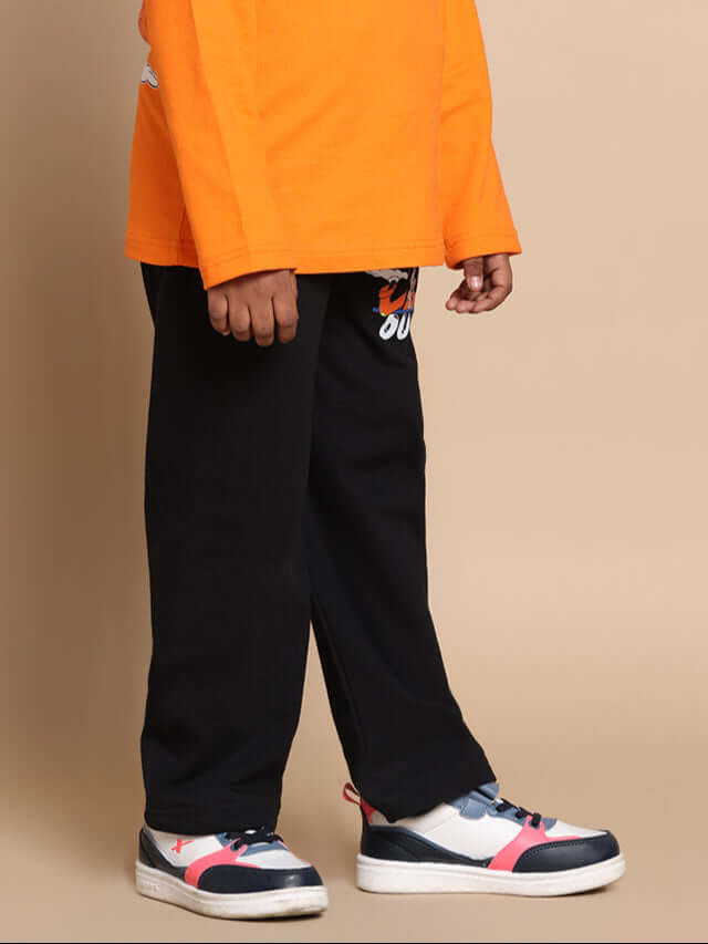 Child wearing black goofy joggers from DUDS, styled with a vibrant orange top and colorful sneakers.