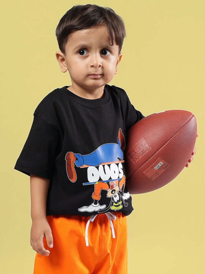 Child wearing Goofy Oversized T-Shirt for Boys Girls Black, holding a football