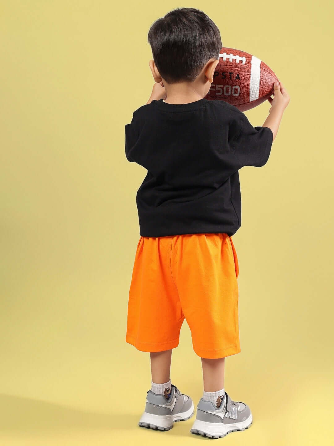 Child wearing GOOFY SUMMER CO-ORD FOR BOYS & GIRLS BLACK-ORANGE holding a football, showcasing playful summer fashion for kids.